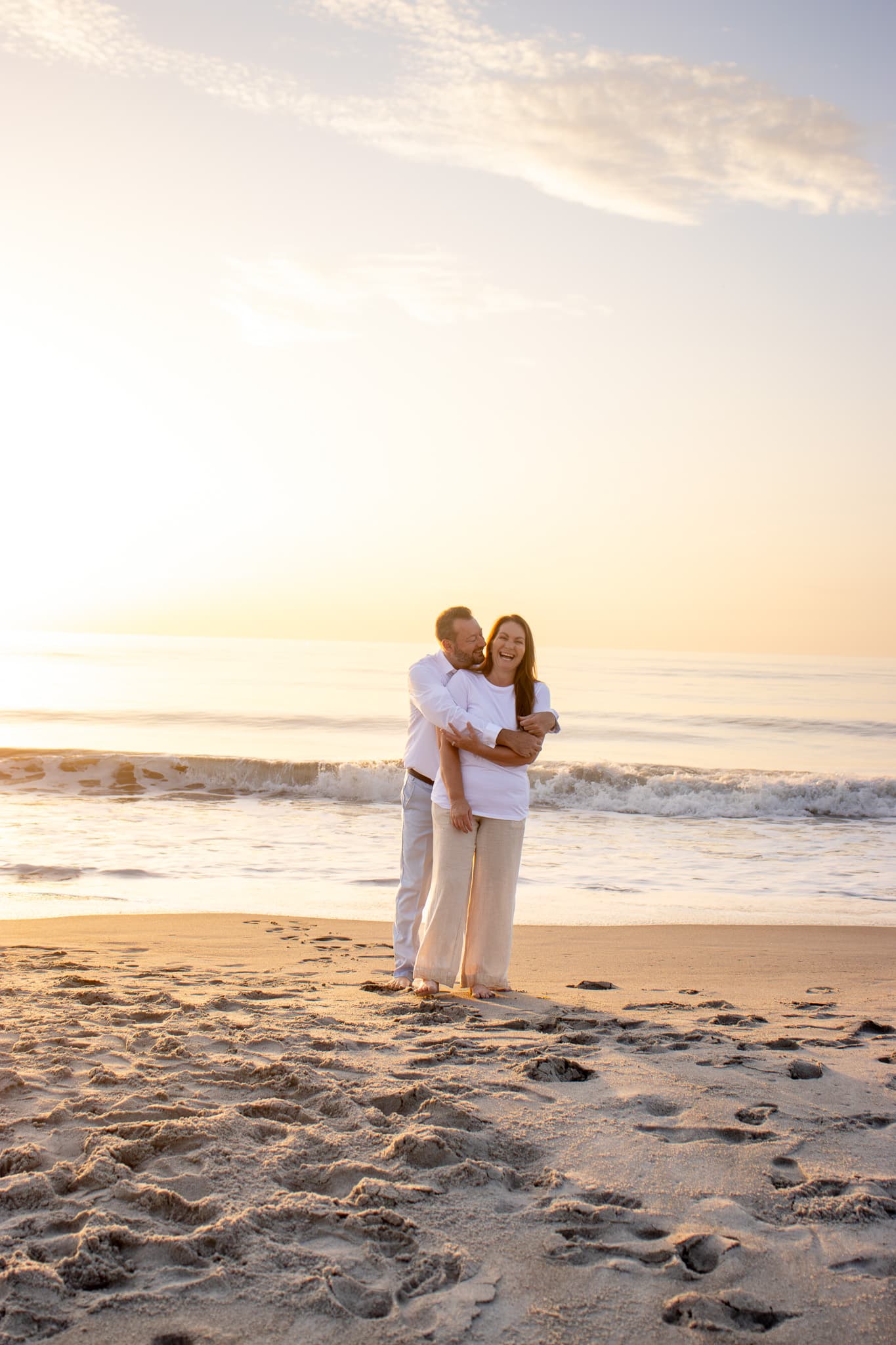 A couple laughing together during a sunrise photography session on a Florida beach