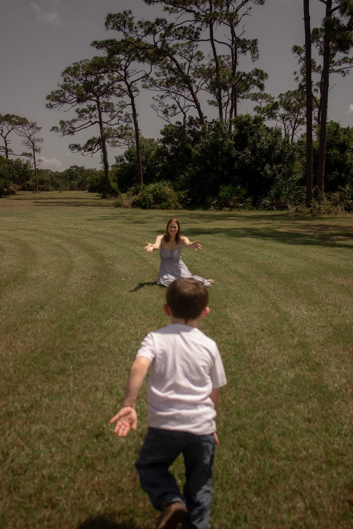 A child running through a field toward a seated parent