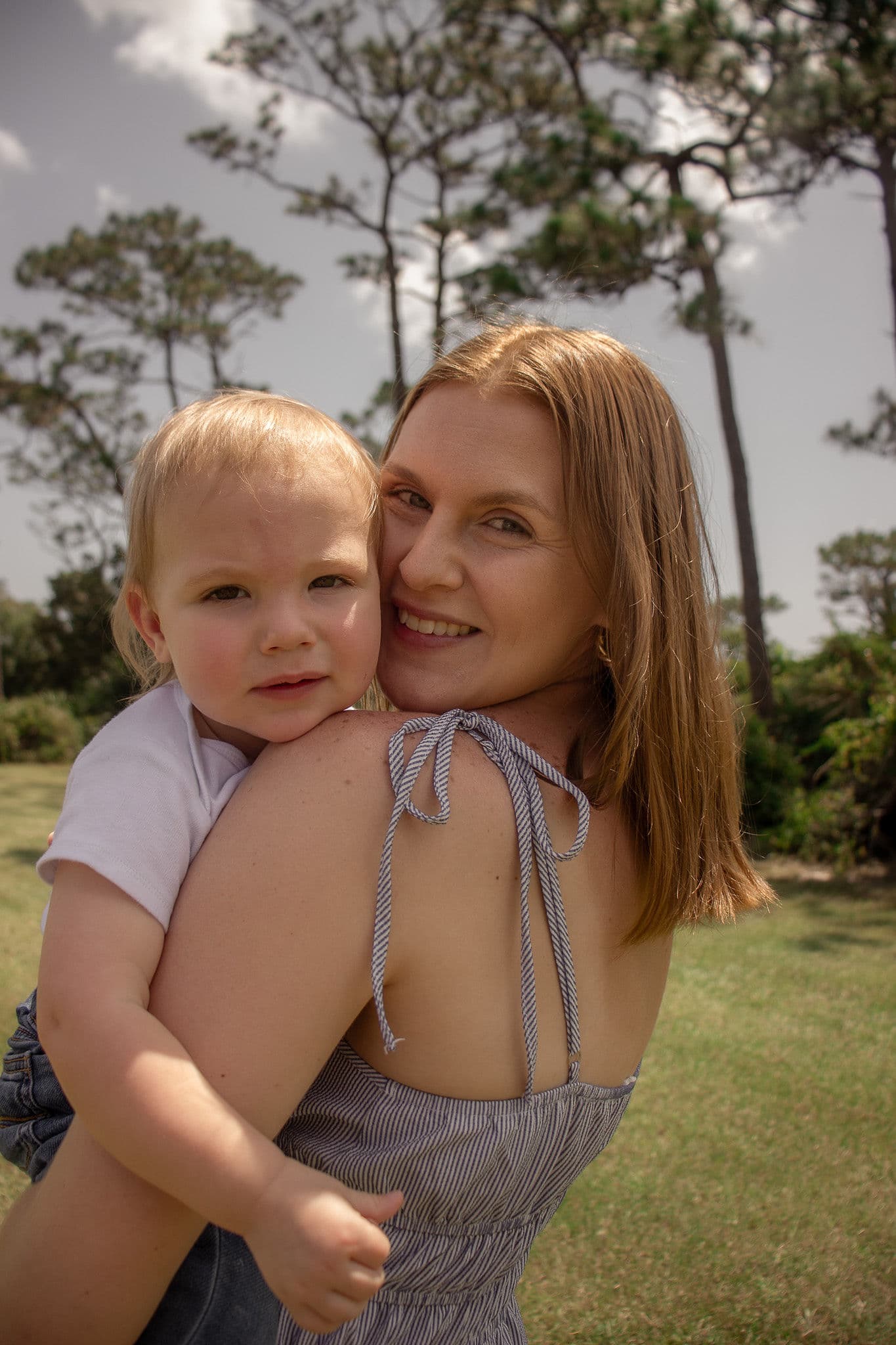 A mother holding a child in a sunlit Florida field